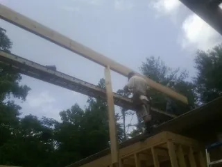 Carpenter setting a ridge beam over a new addition frame — Ice Dam Removal by Roofing Brothers in Altus