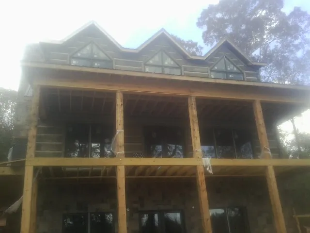 Dormers and porch framing on a large log home under construction — Roof Coating work by our crew in Altus