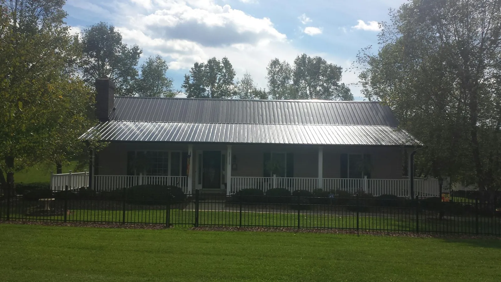 Gray metal roof on a brick ranch with a full width front porch — Gutter Guard Installation work by our crew in Altus