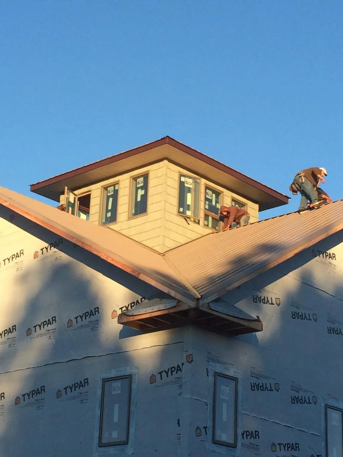 Roofers working around a rooftop cupola on a new metal roof at sunset — Roof Waterproofing in Altus by Roofing Brothers
